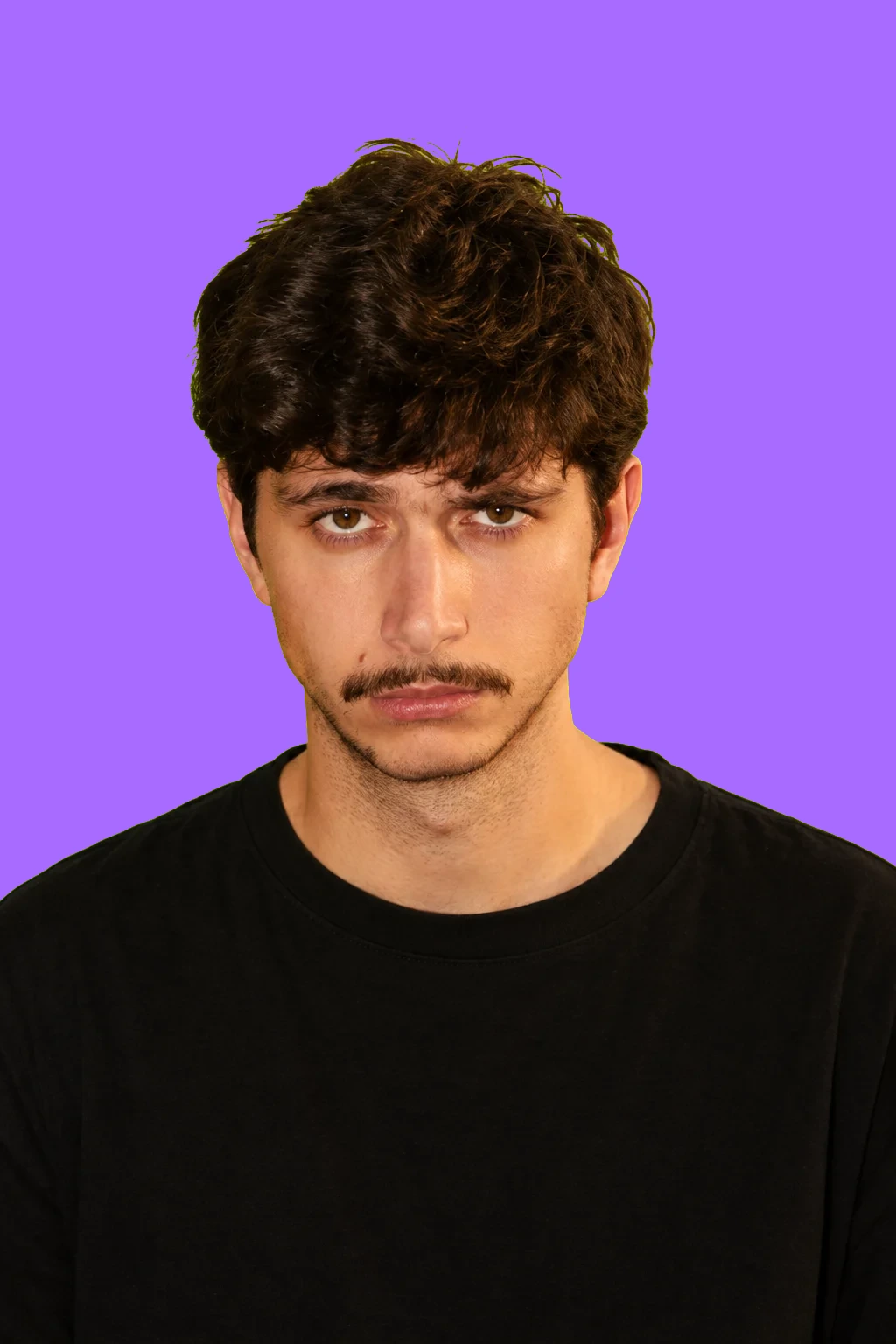 Retrato de Jota, con el pelo oscuro y camiseta negra, sobre el fondo verde lima de Tenderete